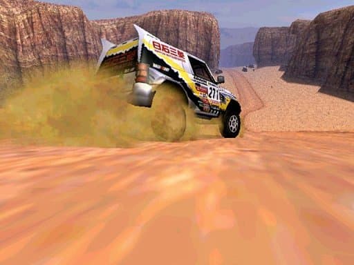 Rally vehicle kicking up dust on a sandy slope between high canyon walls